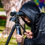 Leofoto BC-01 Stativadapter gebruiker stelt verrekijker op statief af in het veld