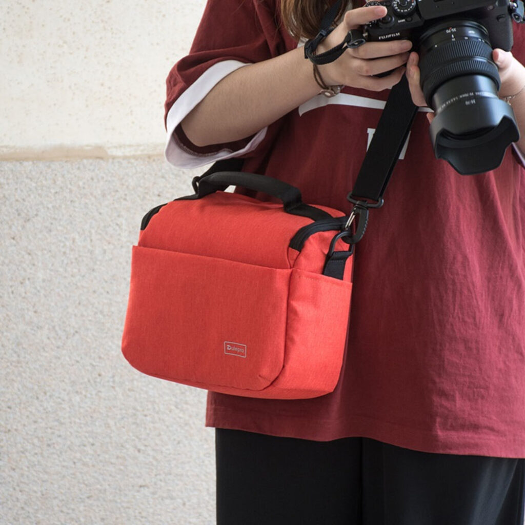 Dulepro Companion Shoulder Bag S22 oranje gedragen door fotograaf met camera in de hand