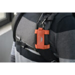 Summit-Creative Speedyclip-riem oranje bevestigd aan borstband van grijs vest met Speedyclip-houder