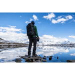 Summit-Creative Tenzing Rolltop Backpack gebruiker buitenstaand met backpack bij een meer in sneeuwgebied