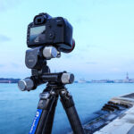 Leofoto GW-01 Statief-gearhead met camera op statief boven stadspanorama met water en brug op de achtergrond.