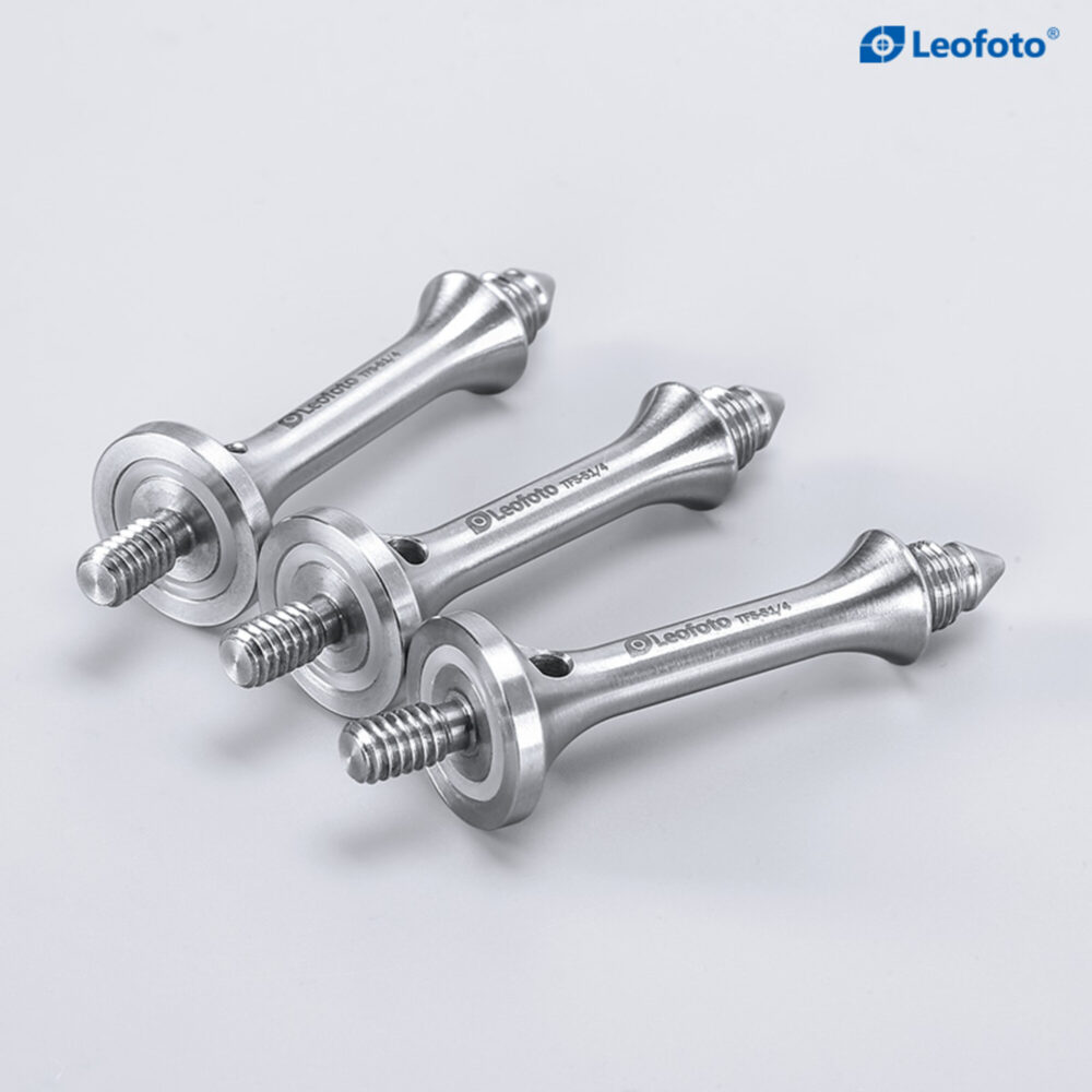 Leofoto S1/4 statiefvoet close-up van drie lange spikes schuin naast elkaar gelegd op neutrale ondergrond.