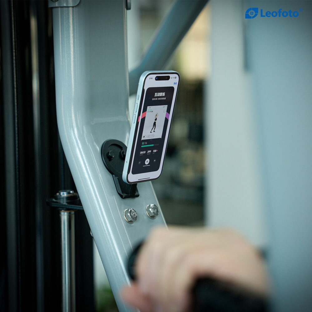 Leofoto PM-05 smartphonehouder in gebruik met smartphone magnetisch bevestigd aan metalen trainingsapparaat in de sportschool.