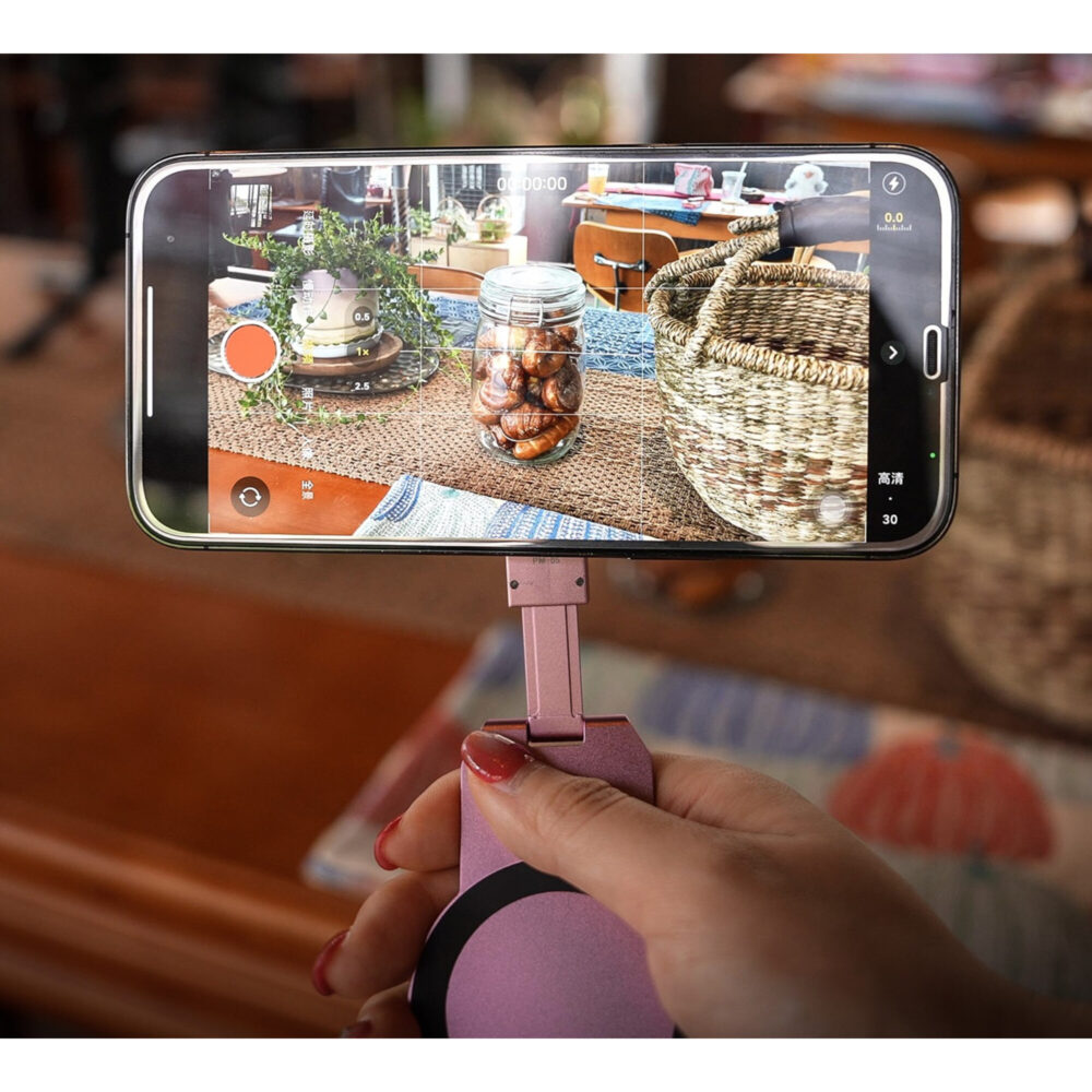 Leofoto PM-05 smartphonehouder roze in gebruik als handgreep met horizontaal gefilmde smartphone tijdens het opnemen.