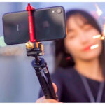 Leofoto PC-20 smartphonehouder rode uitvoering gemonteerd op selfie-stick met horizontaal geklemde smartphone tijdens het filmen.