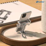 Leofoto PC-3 smartphone houder als tafelezel met smartphone rechtop op een houten dienblad naast accessoires.