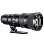 Leofoto NF‑01N objectiefvoet onder Nikon telelens gemonteerd op lange Arca-Swiss statiefplaat in zijaanzicht.