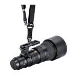 Leofoto NF‑01N objectiefvoet gebruikt met Quick-Release-draagriem, Nikon camera met telelens hangend gedragen aan QD-aansluiting.