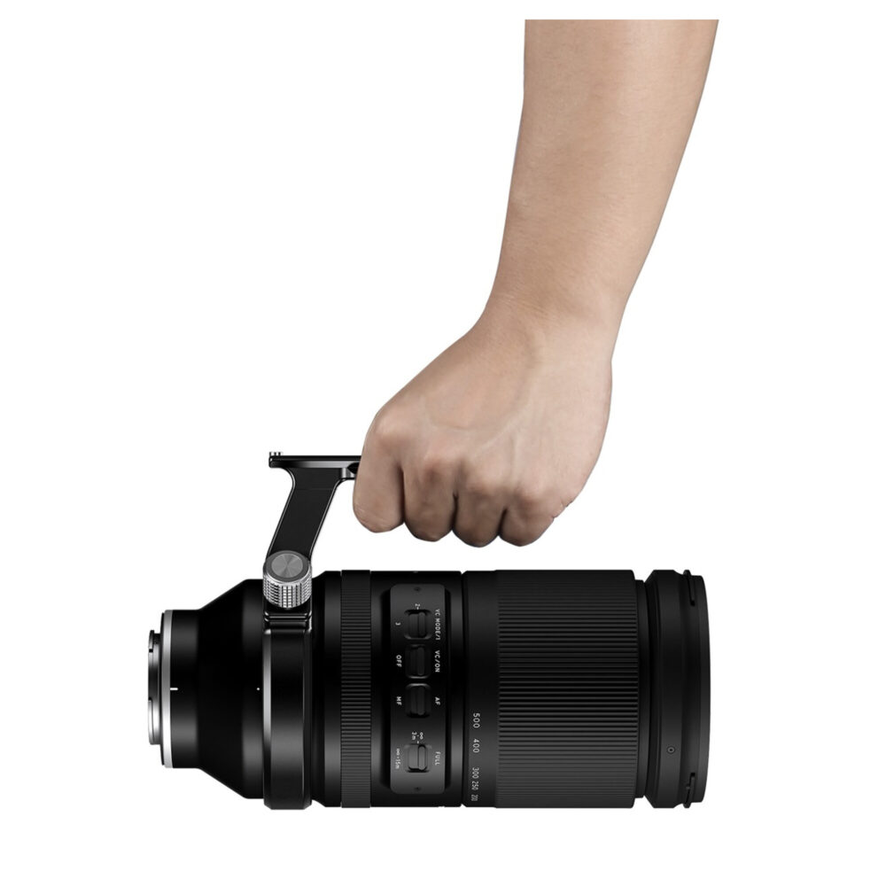 Leofoto TRFC‑01 objectiefvoet in gebruik waarbij een hand de Tamron 150–500mm lens veilig aan de voet draagt.