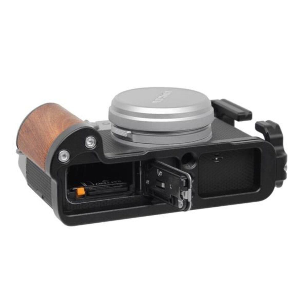 Leofoto LPF-X100V L-bevestiging onderaan Fujifilm X100V gemonteerd met geopend batterijvak en vrije toegang tot aansluitingen.