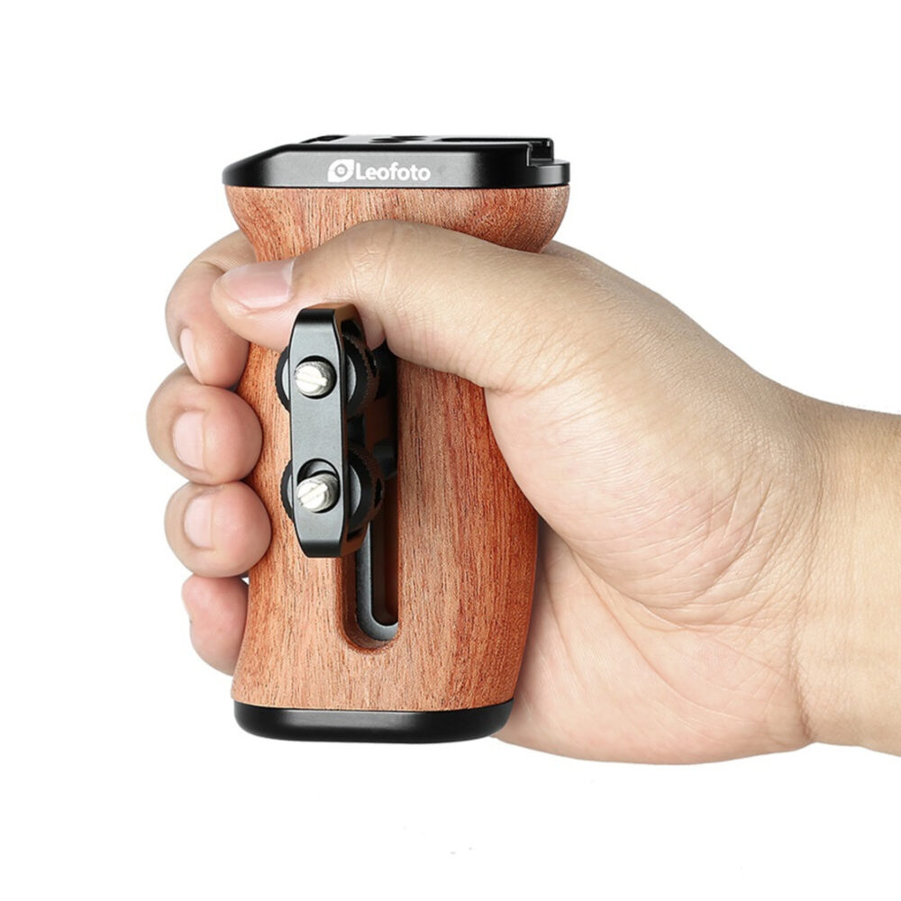 Leofoto CH-3 cameracage houten handgreep in hand gehouden, met zichtbare metalen klem en ergonomische vorm.