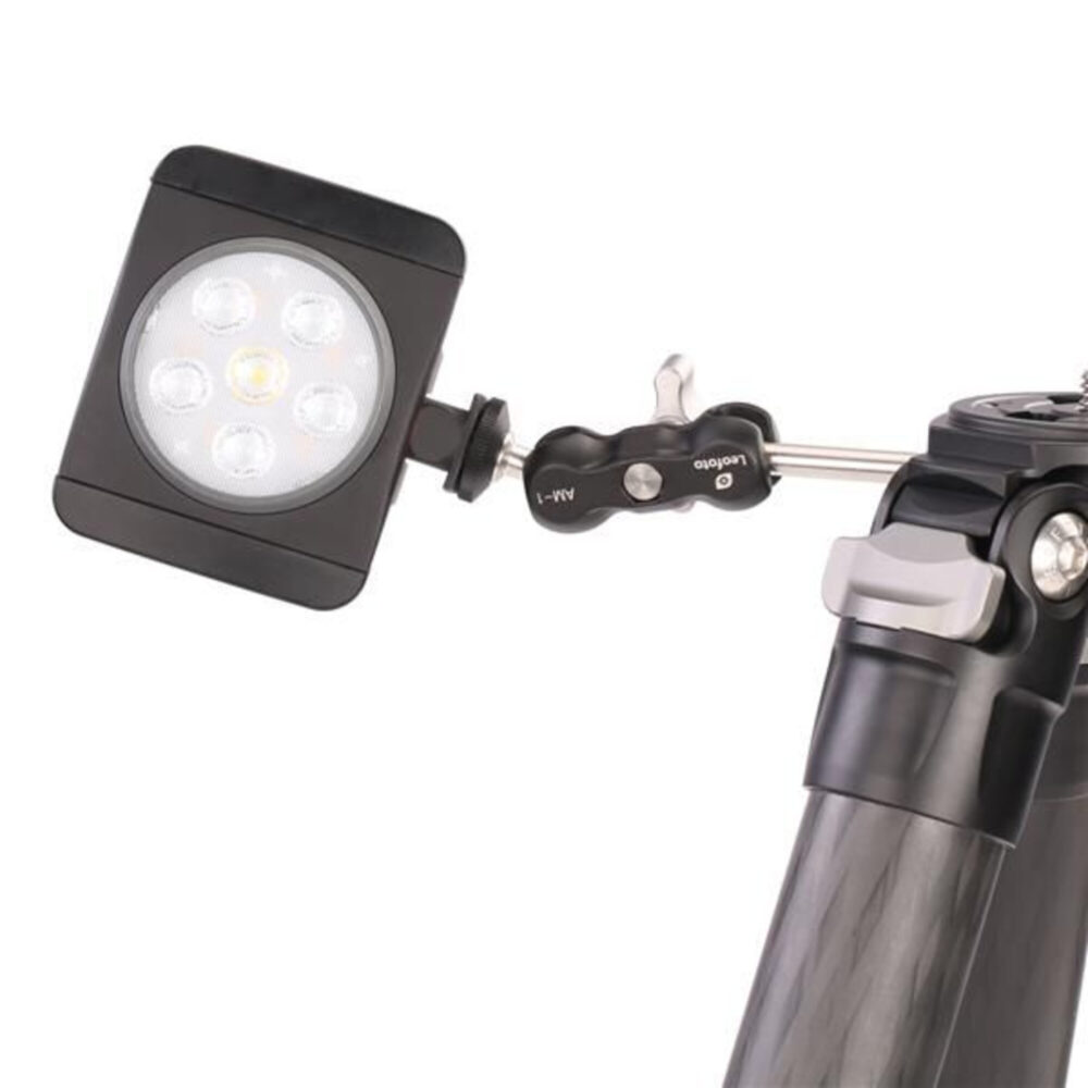 Leofoto AM-1 scharnierende arm gemonteerd op statief met bevestigde LED-lamp voor extra verlichting.