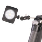 Leofoto AM-1 scharnierende arm gemonteerd op statief met bevestigde LED-lamp voor extra verlichting.