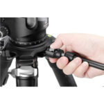 Leofoto AM-4 scharnierende arm bevestiging aan statief waarbij een hand de arm in de statiefbasis draait.