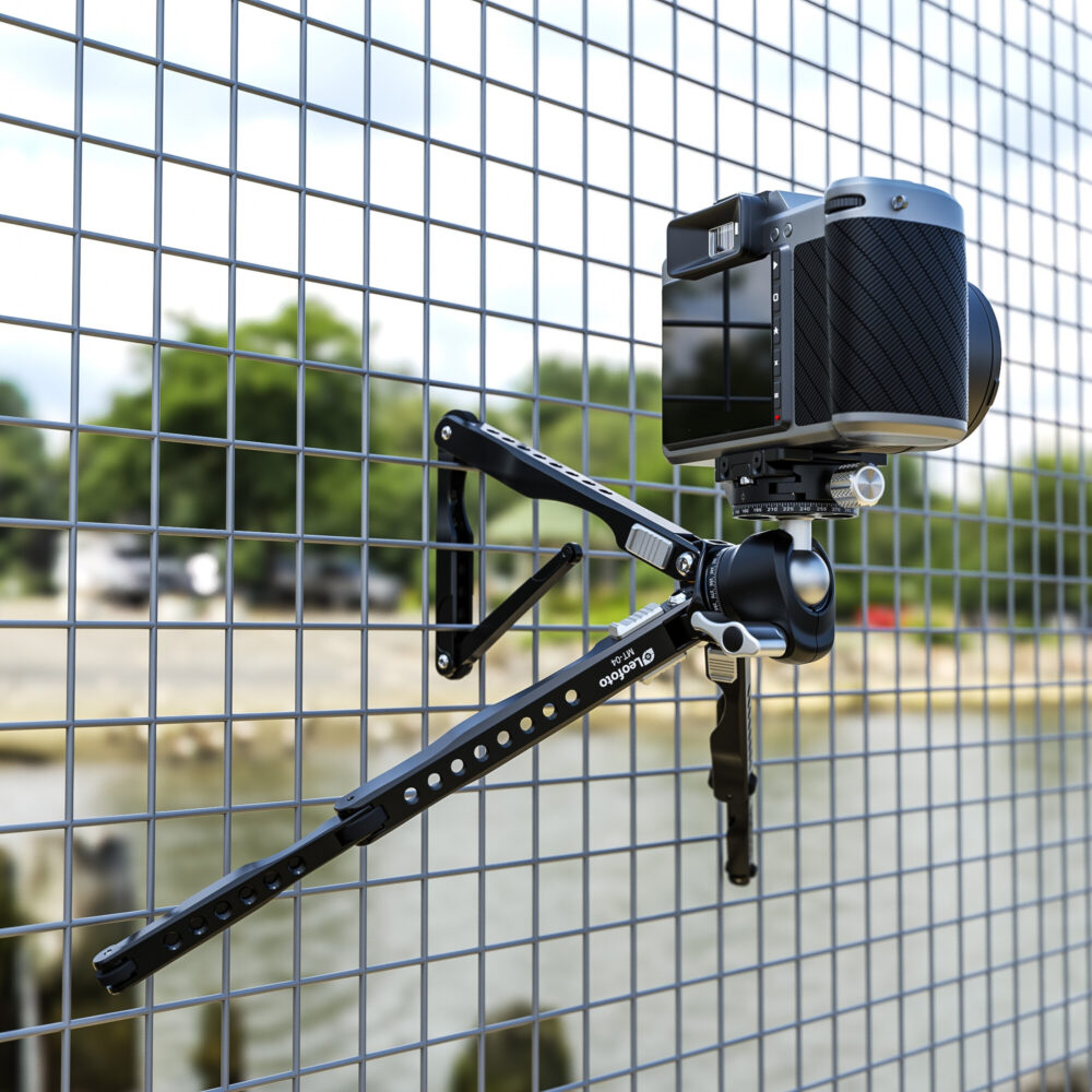 Leofoto MT-04 Tafelstatief met camera bevestigd aan hekwerk, poten om de spijlen gevouwen.