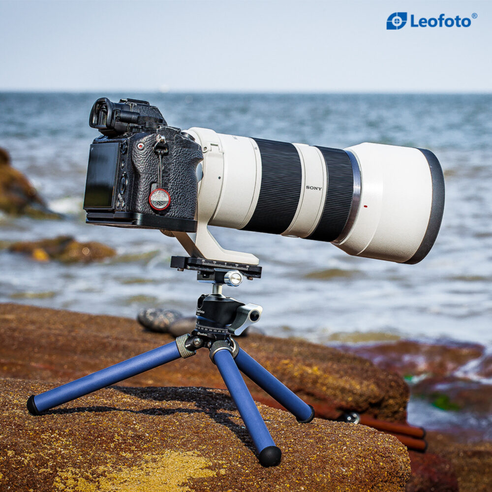 Leofoto MT-02C+LH-22 Tafelstatief blauw in gebruik met camera en telelens op ondergrond buiten.