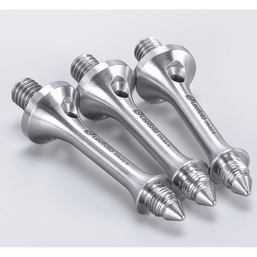 Leofoto S3/8 statiefvoet drie glanzende spikes schuin naast elkaar gelegd op neutrale ondergrond.