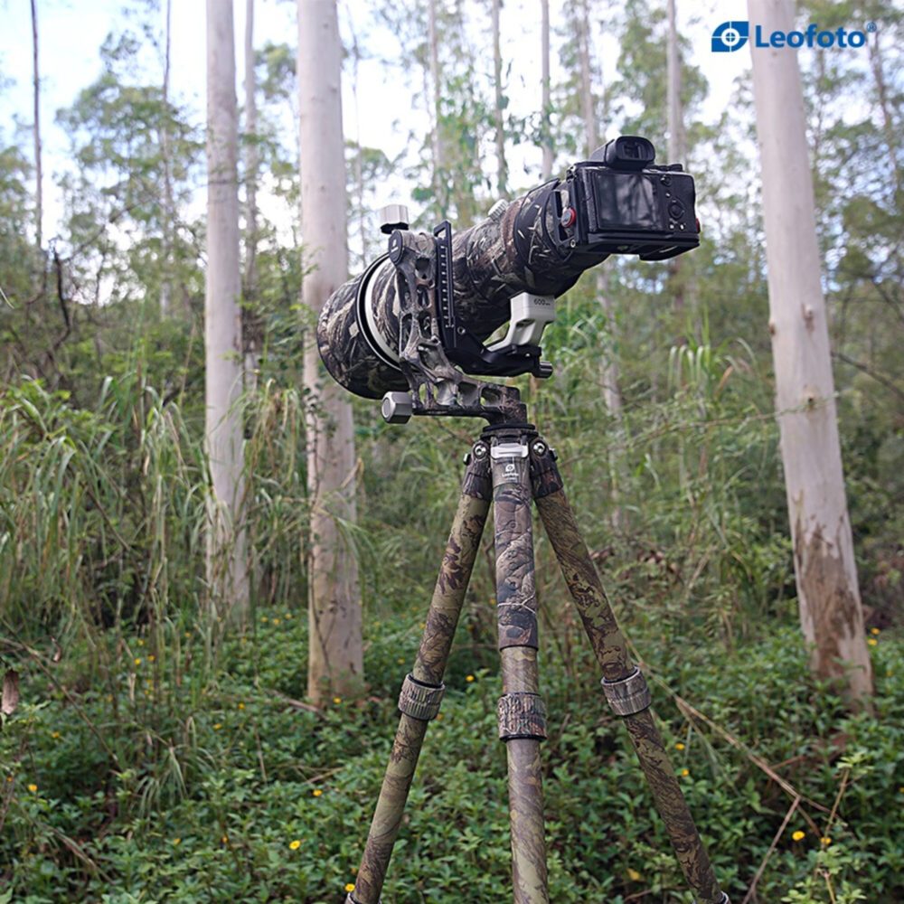 Leofoto LS-365C Tripod full camouflage met zwarte camo-lens en camera op gimbal in bosomgeving.