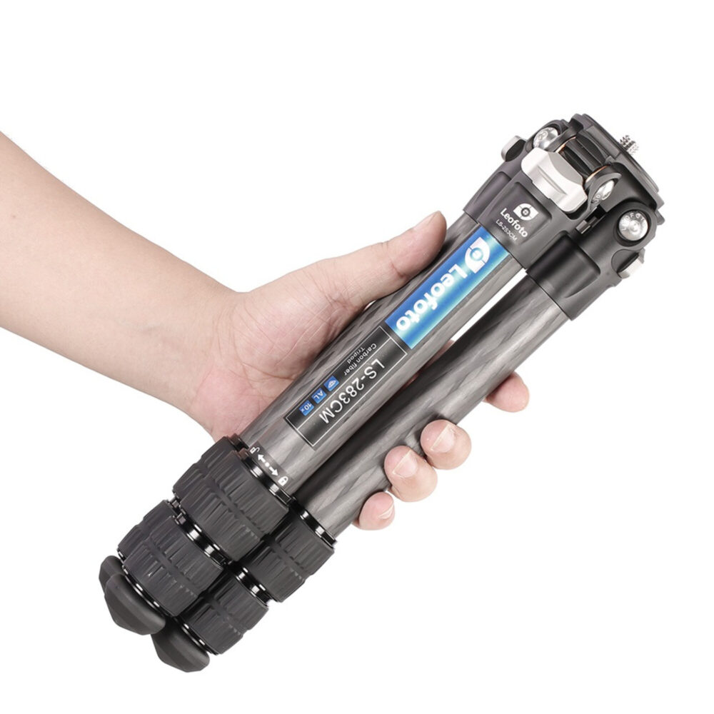 Leofoto LS-283CM Tripod ingeklapt carbon statief in hand gehouden ter illustratie van het compacte formaat.