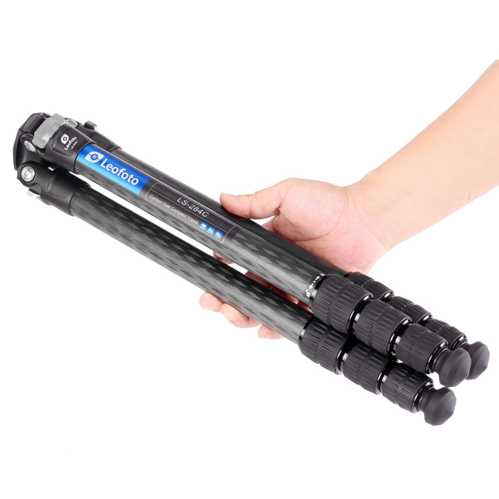 Leofoto LS-284C Tripod compact ingeklapt carbon statief in hand gehouden om reisformaat te tonen.