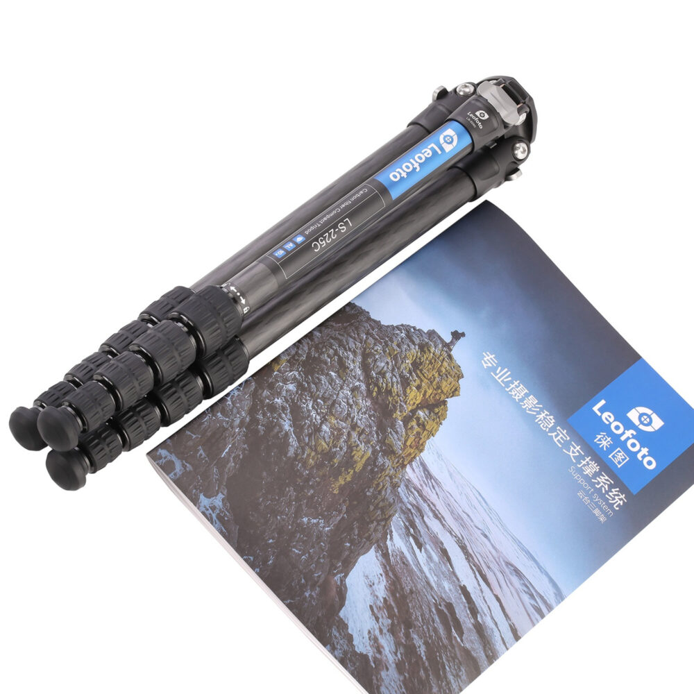 Leofoto LS-225C Tripod ingeklapt naast brochure, toont compact reisformaat.