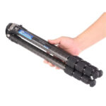 Leofoto LS-284C Tripod compact ingeklapt in een hand om het draagbare formaat te tonen.