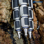Leofoto LP-324C Tripod close-up van blauwe poten met zilverkleurige draaisluitingen en spikes op rots.
