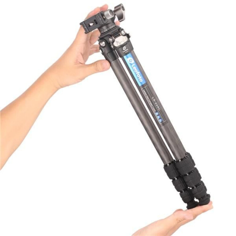Leofoto LS-224C Tripod in twee handen gehouden, laat lichtgewicht carbon constructie zien.