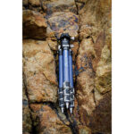 Leofoto LP-284C Tripod liggend tussen rotsen, klaar voor gebruik in kust- of rivieromgeving.