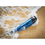 Leofoto LP-284C Tripod statief liggend in nat zand aan zee met opspattend water voor kustfotografie.