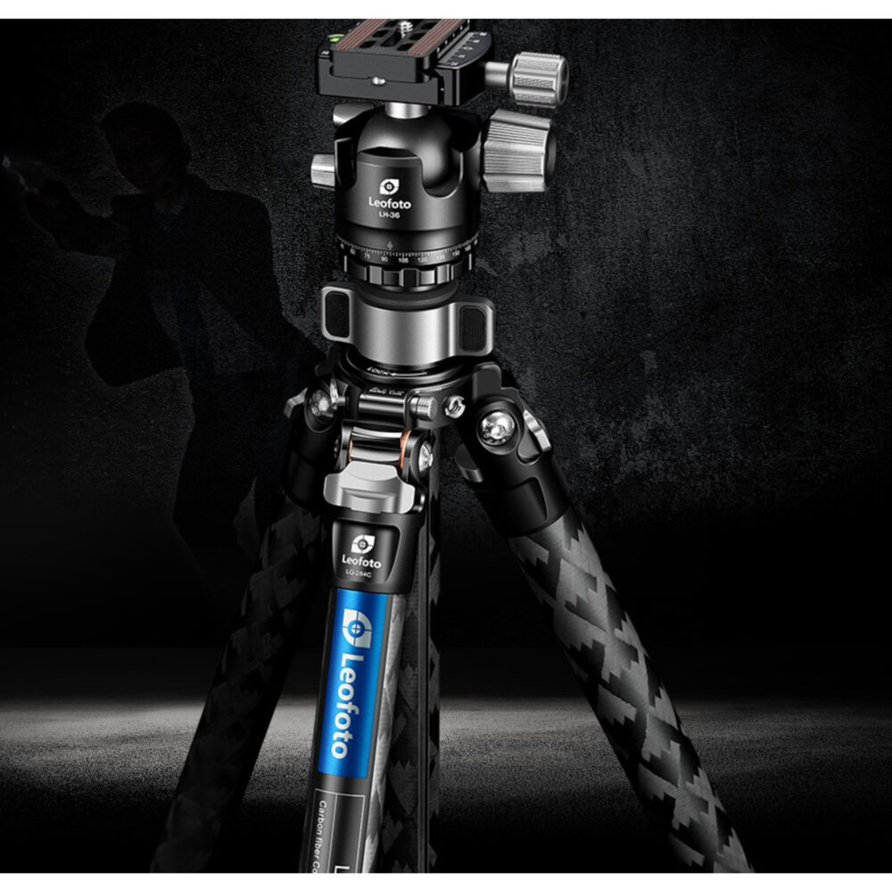 Leofoto LQ-284C Tripod creatief gefotografeerd op donkere achtergrond met silhouet van fotograaf op de achtergrond.