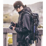 Leofoto LY-224C Tripod lifestylefoto van fotograaf met rugzak waaraan het statief is bevestigd.