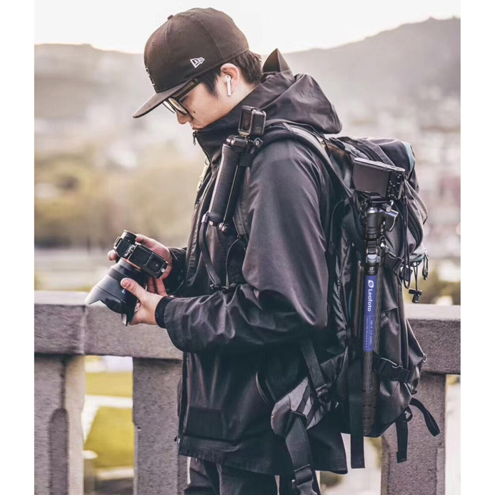 Leofoto LY-224C Tripod lifestylefoto van fotograaf met rugzak waaraan het statief is bevestigd.