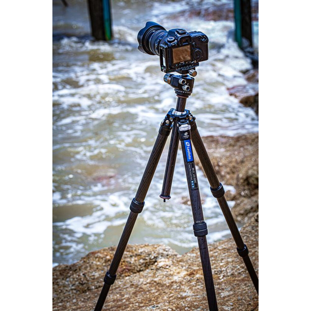 Leofoto LO-284C Tripod opgesteld bij de branding met camera gemonteerd voor stabiele opnames aan zee.
